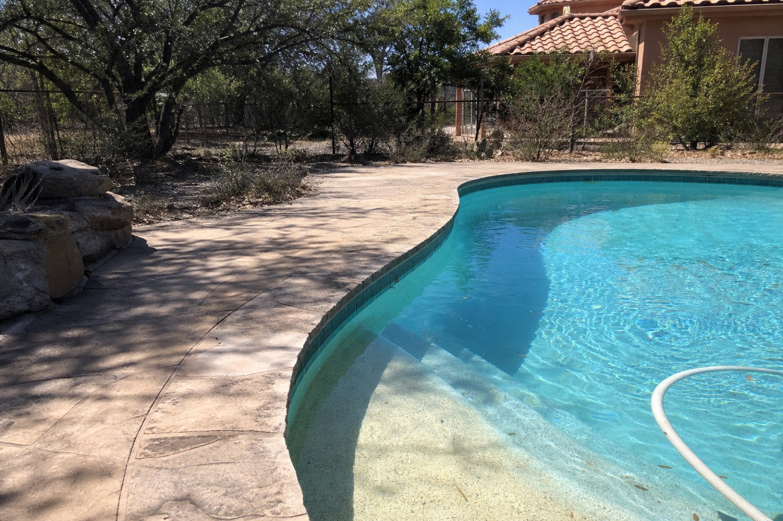 Backyard residential swimming pool with stamped concrete deck and faded teal waterline tile, Fort Worth.