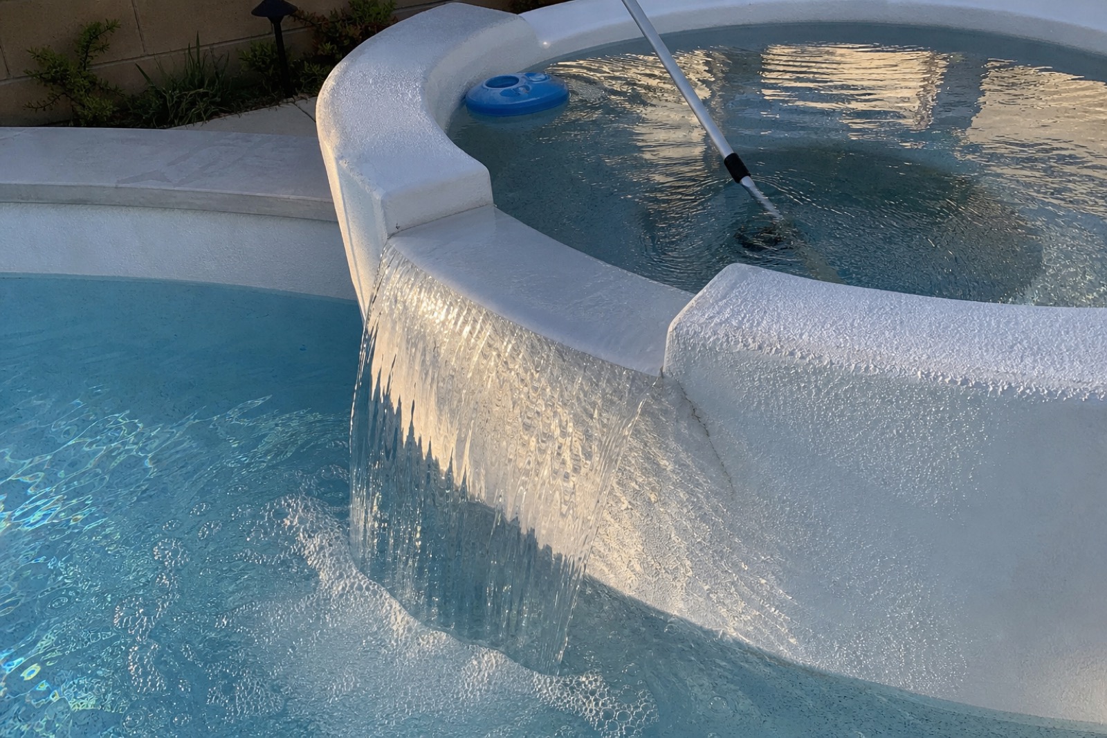 A residential spa overflow cascading into the main pool, being tested by a service technician.