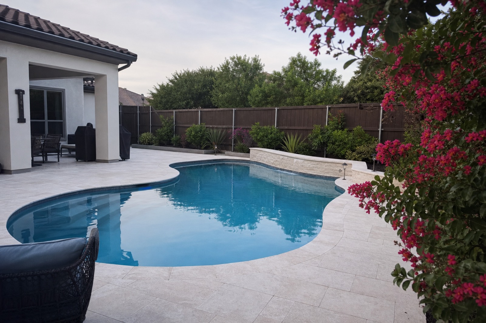 A clean residential pool with deep blue water and a white limestone deck in a Fort Worth backyard.
